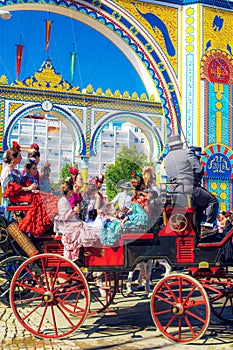 Spanish families in traditional and colorful dress travelling in a horse drawn carriages at the April Fair