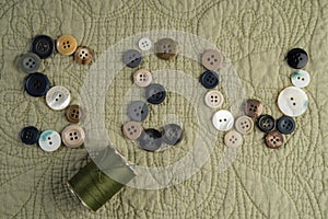 SEW spelled out with buttons, with thread.