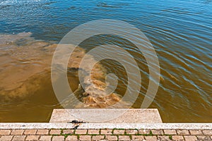 Sewage pipe outfall into the river, water pollution and environmental damage concept