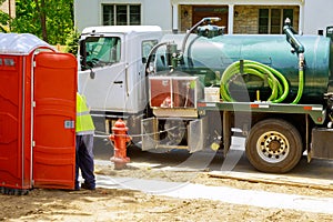 Sewage truck on worker pumping feces out of rental toilet for disposal and cleaning