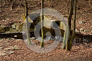 Sewer bridge through a ditch by the road. concrete hole with surroundings of stone paving. grassy slope by the road. has the task photo