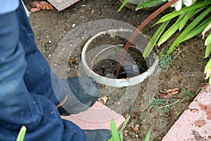 Sewer cleaning. A plumber uses a sewer snake to clean blockage in a sewer line