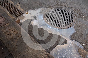 Sewer lid on street with dirty water