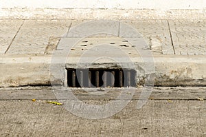 Sewer manhole under sidwalk 0n concrete road.