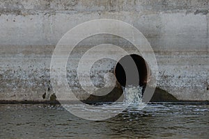 Sewer pipe in a concrete wall from which water flows