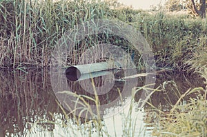 Sewer pipe pour out to the lake/ecology concept: Waste water flow from water pipe into lake