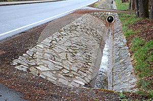 Sewer pipes under the bridge. crossing the ditch by the road. concrete hole with stone paving surroundings. The gutter drains arou