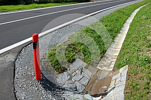 Sewer pipes under the bridge. crossing ditch by side road. concrete hole with stone paving surroundings. The gutter drains around