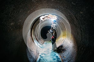 Sewer tunnel worker examines sewer system damage and wastewater leakage