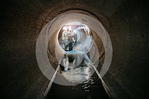 Sewer tunnel workers examines sewer system damage and wastewater leakage photo