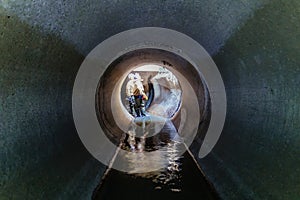 Sewer tunnel workers examines sewer system damage and wastewater leakage photo