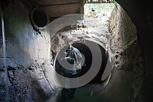 Sewer worker in underground flooded sewage collector