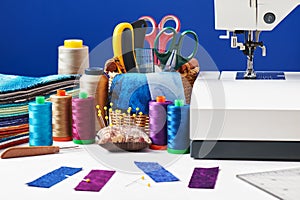 Sewing accessories in a basket and spools of threads next to sew