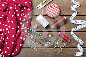 Sewing accessories and fabric on wooden background. Sewing threads, needles, pins, fabric, buttons and sewing centimeters. top