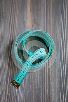 Sewing accessories Ã¢â¬â the green centimetric measuring tape, tailor tape on a wooden background photo