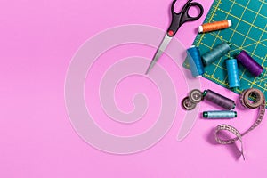 Sewing accessories on a plastic pink background. Top view, flatlay