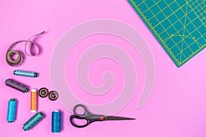 Sewing accessories on a plastic pink background. Top view, flatlay