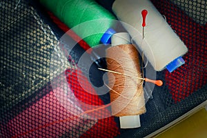 Sewing accessories, reels with colored threads, needles and pins, blurred background