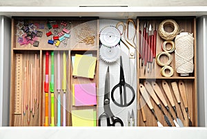 Sewing accessories and stationery in open desk drawer