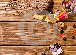 Sewing accessories such as threads and needles on a wooden table. Copy space.