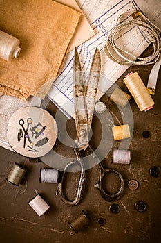 Sewing and craft tools - old scissors, bobbins with thread and needles on wooden table