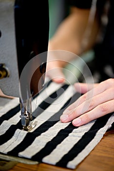 Sewing, fabric and hands of person at machine with textile, fashion and process closeup in factory. Manufacturing