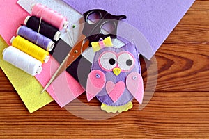 Sewing a felt owl toy. Purple owl decorated with bow, buttons and heart