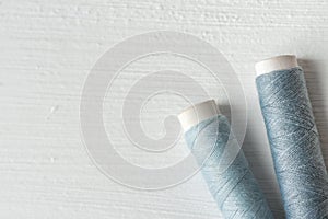 Sewing gray threads on cardboard spools on white painted wood background. Crafts hobbies