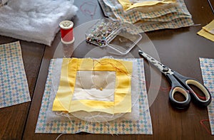 Sewing of handmade patchwork hot pads with scissors, pool of threads