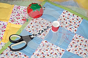 Sewing of handmade patchwork placemats with scissors, pool of threads and pin cushion