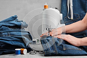 Sewing jeans on sewing machine in tailor workshop. Jeans repair