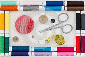 Sewing kit colorful threads frame top view white linen background