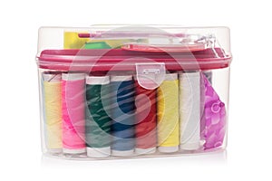 Sewing kit with different spools of thread in a transparent plastic box isolated on a white background