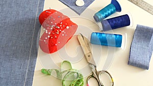 Sewing kit, sewing scissors, bobbins with thread, pincushion with needles, centimeter on a white table background