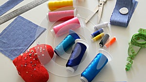 Sewing kit, sewing scissors, bobbins with thread, pincushion with needles, centimeter on a white table background