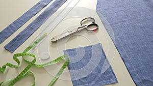 Sewing kit, sewing scissors, rags of blue fabric, centimeter on a white table background. Sewing workshop, toy factory