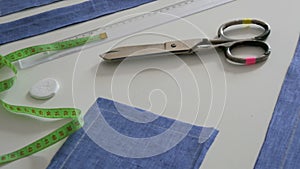 Sewing kit, sewing scissors, rags of blue fabric, centimeter on a white table background. Sewing workshop, toy factory