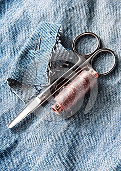 Sewing kit from threads, scissor and needle on jeans backround