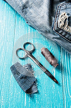 Sewing kit from threads, scissor and needle on jeans wooden backround