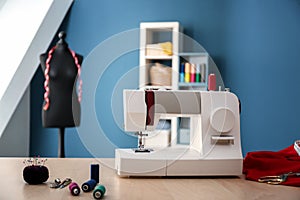 Sewing machine with accessories on table in tailor\'s workshop