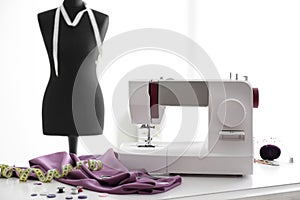 Sewing machine with accessories on table in tailor\'s workshop