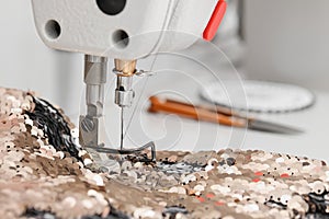 Sewing machine and beautiful fabric with paillettes indoors, closeup