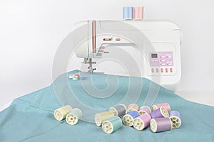 Sewing machine and colorful thread rolls, scissors, fabric and a