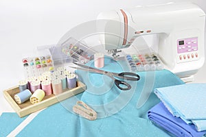 Sewing machine and colorful thread rolls, scissors, fabric and a