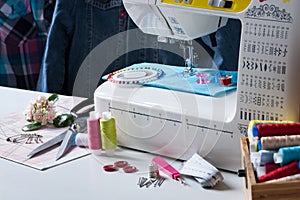 Sewing Machine With Different Accessories On White Table.