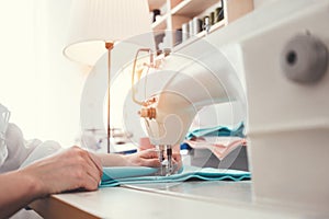 Sewing machine and female hands of dressmakers close-up. Young businesswoman working in clothes design bureau. Small business