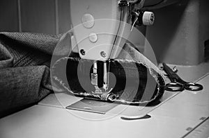 Sewing machine and jeans in sewing workshop. monochrome