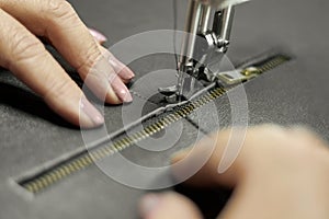 Sewing machine in a leather workshop in action with hands working with a leather details