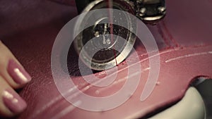 Sewing machine in a leather workshop in action with hands working on a leather details for shoes. Macro shot of women`s