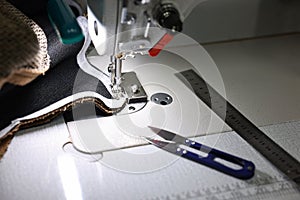 Sewing machine and other tools on white table in professional workshop, closeup